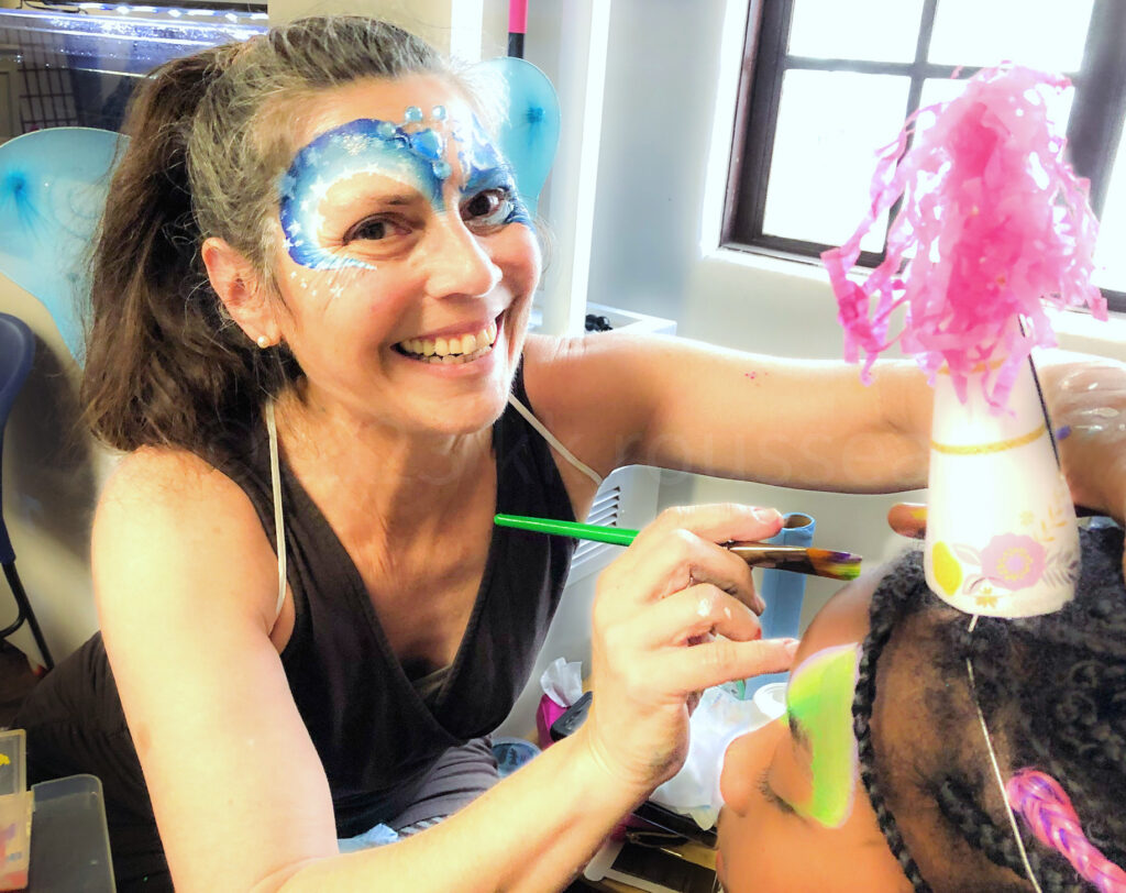 Kimbers smiling and painting kid in party hat